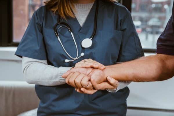 ICU nurse holds patient's hand